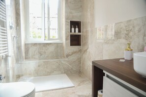 Un bagno con doccia, toilette, lavandino e finestra.