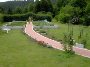 Ein angelegter Garten mit einem gewundenen Pfad, Bänken und verschiedenen Pflanzen.