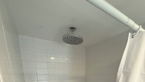 A small, tiled shower stall with a showerhead and a drain. - Cozy 1-bedroom apartment in tranquil Bronx with AC and free parking (Bronx)