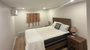 A bedroom with a bed, bedside table, lamp, and a window with curtains. - Cozy 1-bedroom apartment in tranquil Bronx with AC and free parking (Bronx)