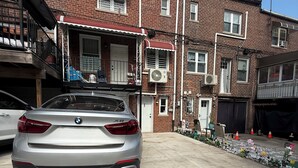 A silver BMW parked in a residential driveway with a brick building in the background. - Cozy 1-bedroom apartment in tranquil Bronx with AC and free parking (Bronx)