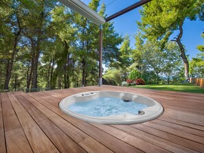 A hot tub on a wooden deck with a pergola overhead, surrounded by trees and a well-maintained lawn. - Luxusvilla mit Meerblick und privatem beheiztem Pool und Whirlpool für bis zu 1 by Interhome (Kassandrino)