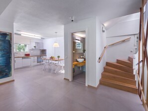 Eine moderne Küche mit weißen Schränken, einem Essbereich mit Tisch und Stühlen sowie einer Holztreppe.
