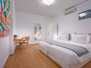 Ein Schlafzimmer mit Bett, Schreibtisch, Stuhl und einem großen Fenster.