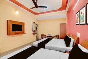 A hotel room with two beds, a ceiling fan, a flat-screen TV, a small table with a tray, and a mirror. - Deluxe Room North Star Residency (Dehradun)