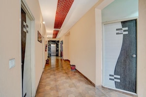 A hallway with a tiled floor, a door with a number sign, and a red ceiling. - Deluxe Room North Star Residency (Dehradun)