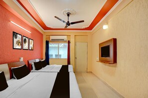 A hotel room with two beds, a ceiling fan, an air conditioning unit, and a television mounted on the wall. - Deluxe Room North Star Residency (Dehradun)
