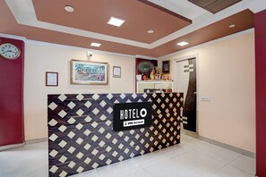 Un comptoir d'accueil d'hôtel avec un motif décoratif, une horloge et des œuvres d'art encadrées accrochées au mur.