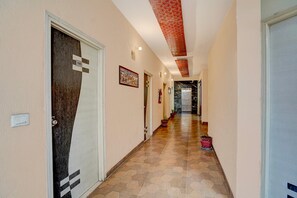 Ein Korridor mit sechseckigem Bodenmuster, einer Tür mit Nummernschild und einem an der Wand befestigten Feuerlöscher.