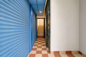 A corridor with blue shutters, a checkered floor, and a tiled wall. - Deluxe Room North Star Residency (Dehradun)