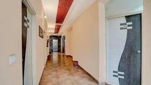 A hallway with a tiled floor, a door with a number sign, and a red ceiling. - Deluxe Room North Star Residency (Dehradun)