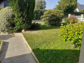 A residential garden with a lawn, various shrubs, and a tall tree. - Les Mésanges 15 min from the beaches (Bricquebec-en-Cotentin)