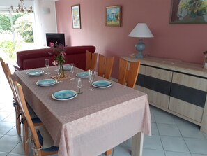 Una zona de menjador amb una taula preparada per a quatre, cadires, un sofà, un armari i una làmpada.
