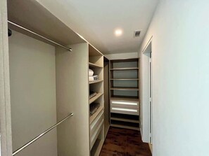A narrow hallway with a built-in closet featuring multiple shelves and drawers.