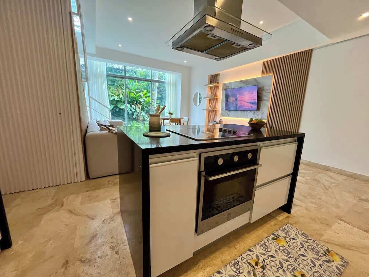 Cocina moderna con horno empotrado, microondas y un amplio ventanal con vistas a zonas verdes.