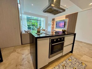 A modern kitchen with a built-in oven, a microwave, and a large window providing a view of greenery outside.