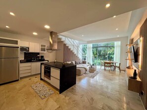 A modern kitchen with a central island, built-in appliances, and a staircase leading to a balcony.