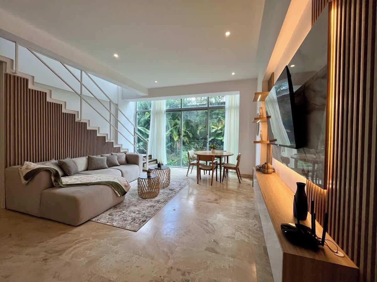 Una sala de estar moderna con sofá, mesa de centro y zona de comedor.