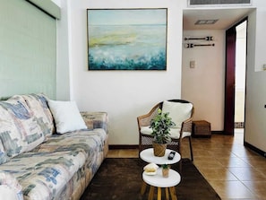 Ein Wohnzimmer mit einer Couch, einem Sessel, einem Couchtisch und einem Bild an der Wand.