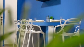 A dining area with a blue table and white chairs.