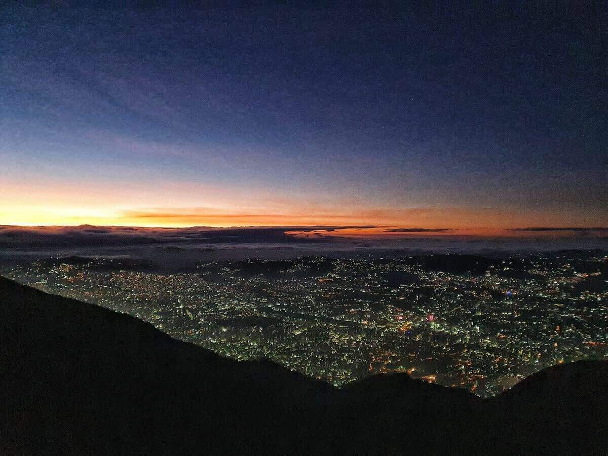 A nighttime cityscape with a view of the city lights and a clear sky.