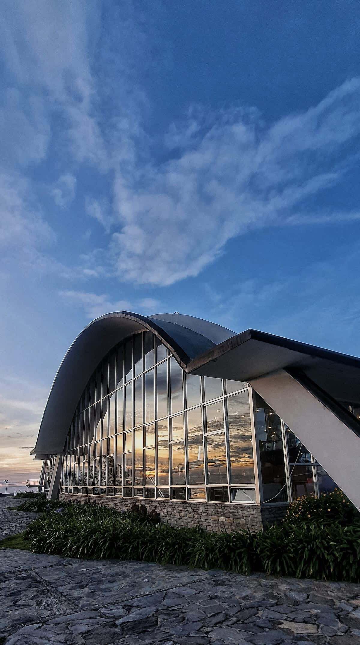 Un edificio moderno con techo curvo y grandes ventanales.