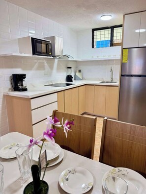 Una cocina moderna con armarios blancos, un refrigerador de acero inoxidable y un comedor con una mesa lista para dos.
