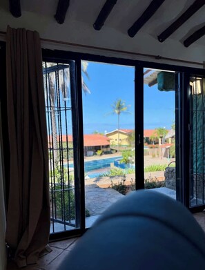 A room with a view of a swimming pool and palm trees outside. - Apartamento familiar con piscina en Pampatar (Pampatar)