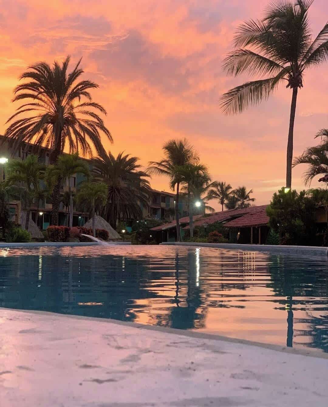 Ein Hotelpool mit Palmen und Gebäuden im Hintergrund.