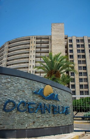 Un edificio con un letrero que dice 'OCEANBLUE' y una palmera frente a él.