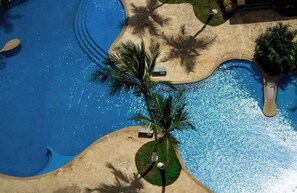 Eine Luftaufnahme eines Swimmingpools mit Palmen und Liegestühlen.
