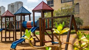 Ein Spielplatz mit Rutschen und Klettergerüsten vor Wohngebäuden.