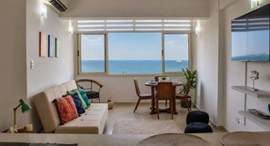 Una sala de estar con sofá, una mesa de comedor y vista al mar.