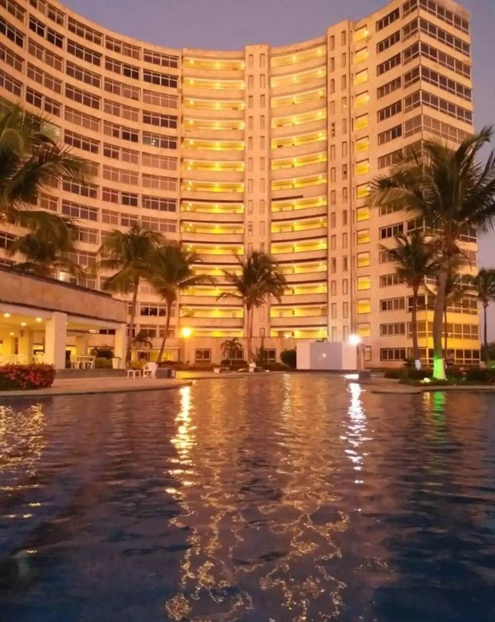 Un hotel a più piani con una piscina in primo piano.