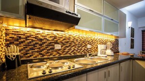 Een moderne keuken met een zwart aanrecht, roestvrijstalen apparatuur en een mozaïek achterwand.