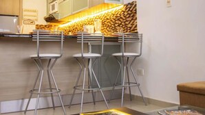Een moderne keuken met een ingebouwde magnetron, een houten aanrecht en een bar voorzien van krukken.