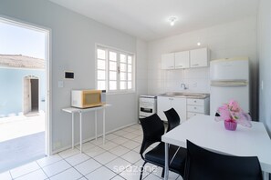 Eine moderne Küche mit weißen Schränken, einer Mikrowelle und einem Spülbecken. Es gibt einen Esstisch mit Stühlen und eine Blumenvase.