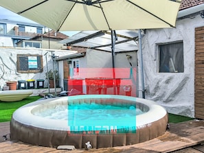 Un jacuzzi en un patio trasero con una pérgola.