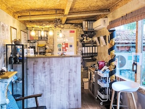 Un interior rústico con techo de madera, una zona de bar con botellas y una pared de piedra.