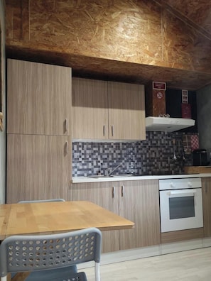 A kitchen with wooden cabinets, a tiled backsplash, a stainless steel sink, and a built-in oven. - Rubin Charme Häuser 10 D by Interhome (Porto)