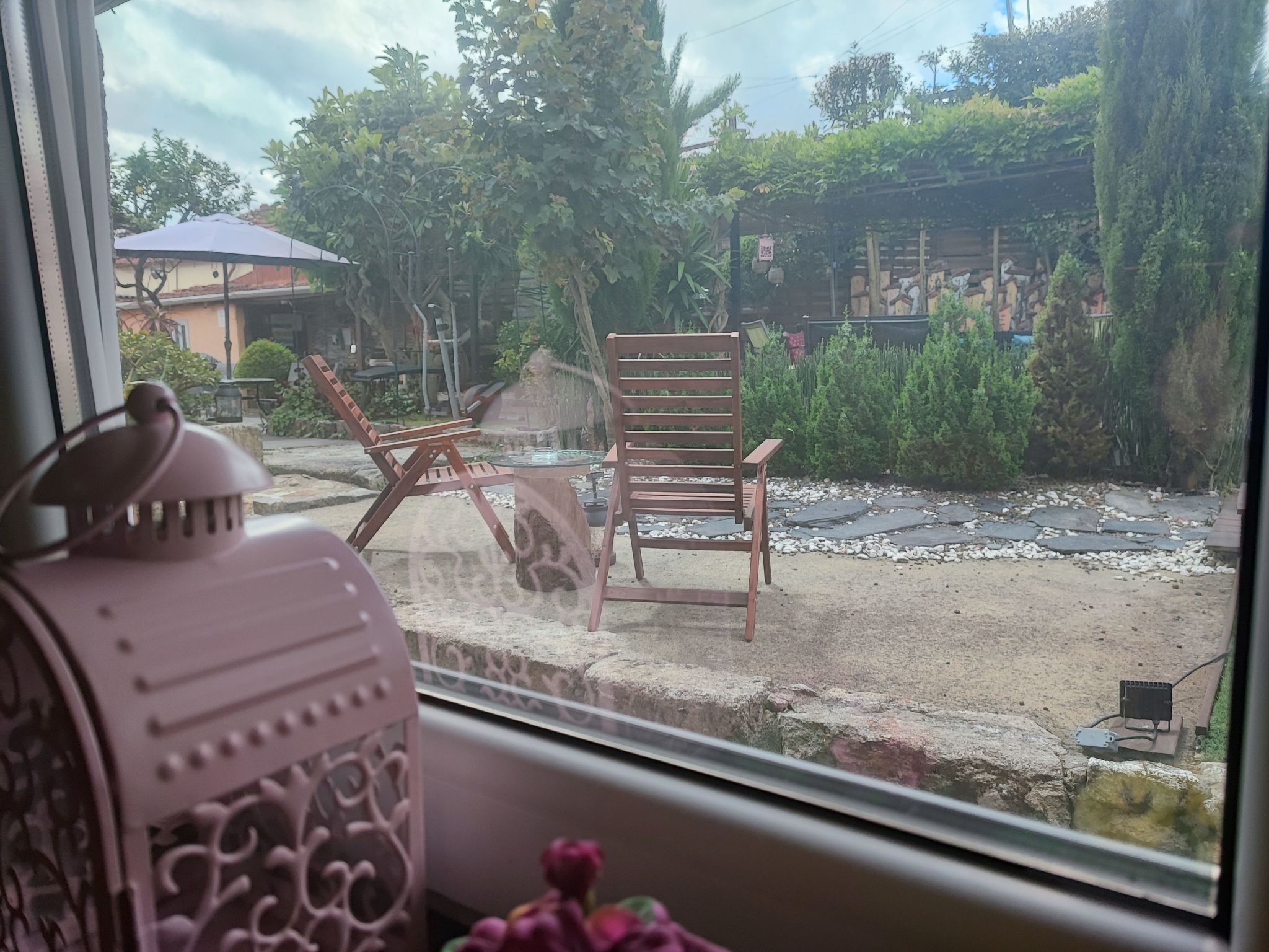 Une vue à travers une fenêtre, avec une chaise et un objet décoratif sur le rebord.