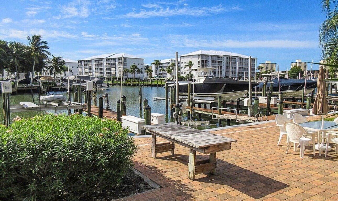 A marina with boats docked, a pool, and a patio area with tables and chairs.