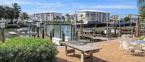 Un port de plaisance avec des bateaux amarrés, une piscine et un espace extérieur aménagé avec des tables et des chaises.