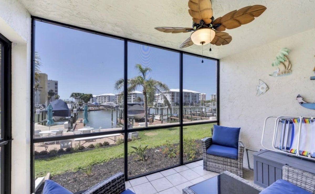 A room with a large window, a ceiling fan, and a view of a marina.