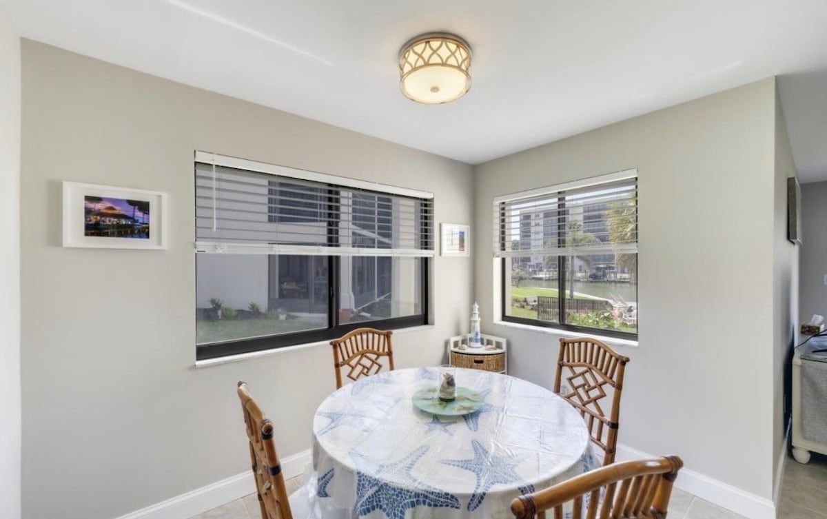 A dining area with a round table, chairs, and a view through the window.