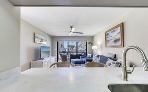 A modern kitchen with a marble countertop, a built-in sink, and a ceiling fan. - Estero Yacht & Racquet 210 (Fort Myers Beach)