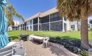 Ein Gebäude mit einer überdachten Terrasse, Sitzgelegenheiten und einem Grill.
