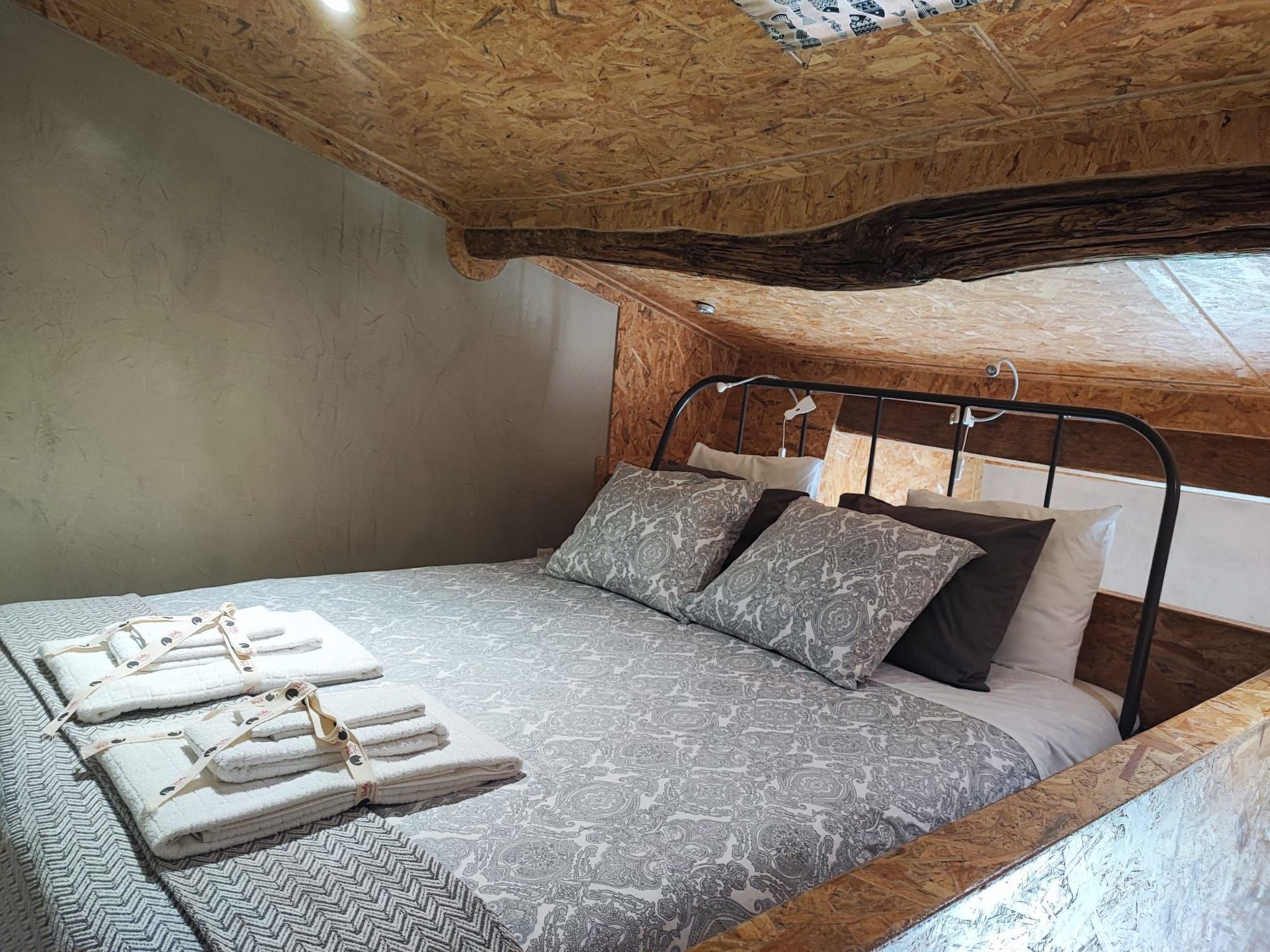 Um quarto com cama, almofadas e toalhas dobradas.