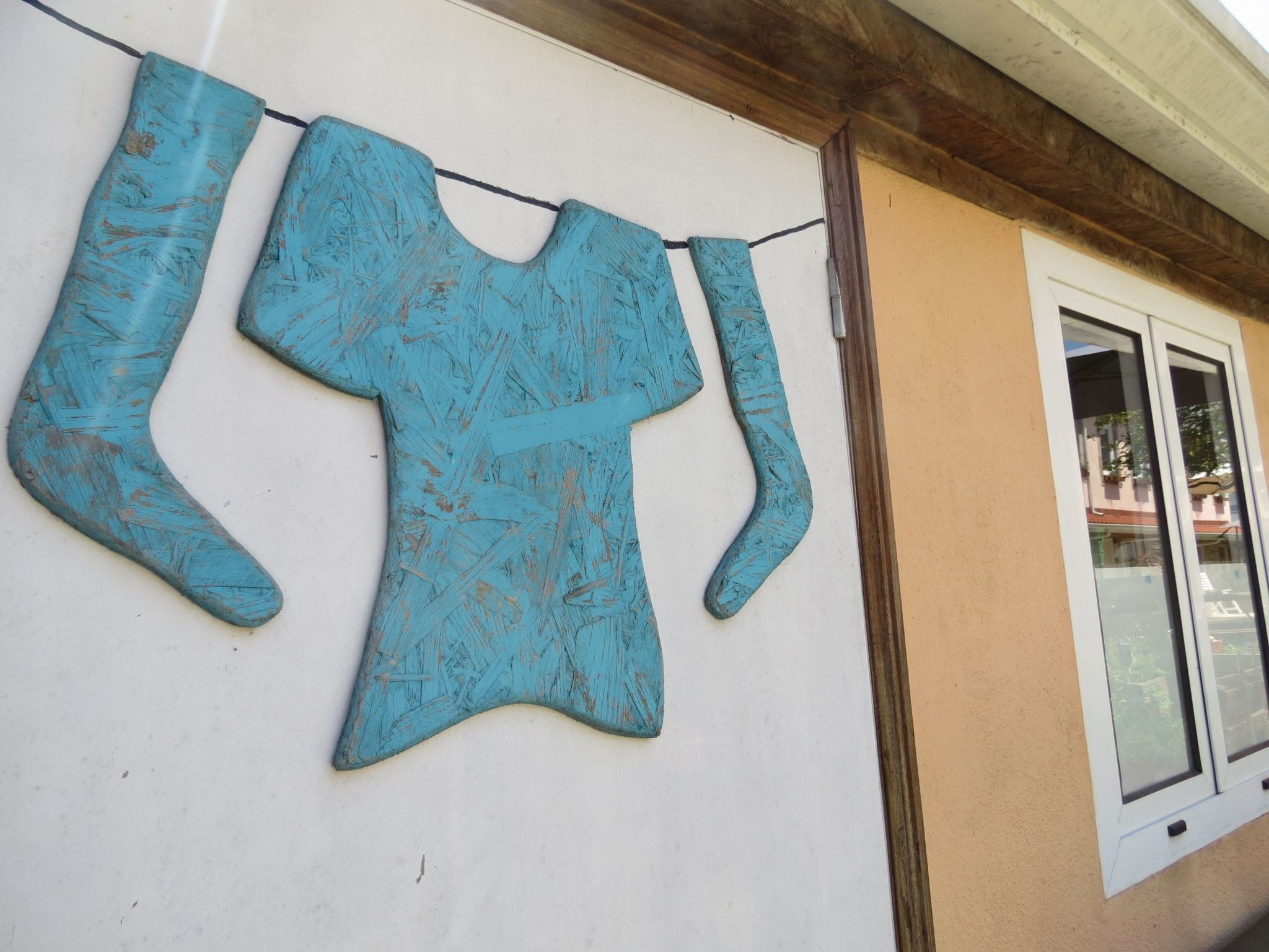 A building exterior with a window and a clothesline with a blue garment.