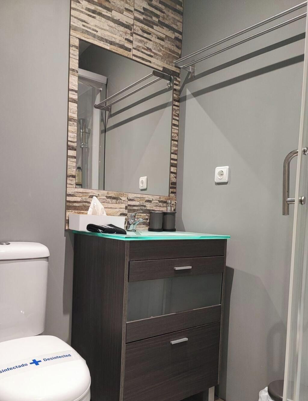 Une salle de bain équipée de toilettes, d’un miroir, d’un lavabo et d’une douche.